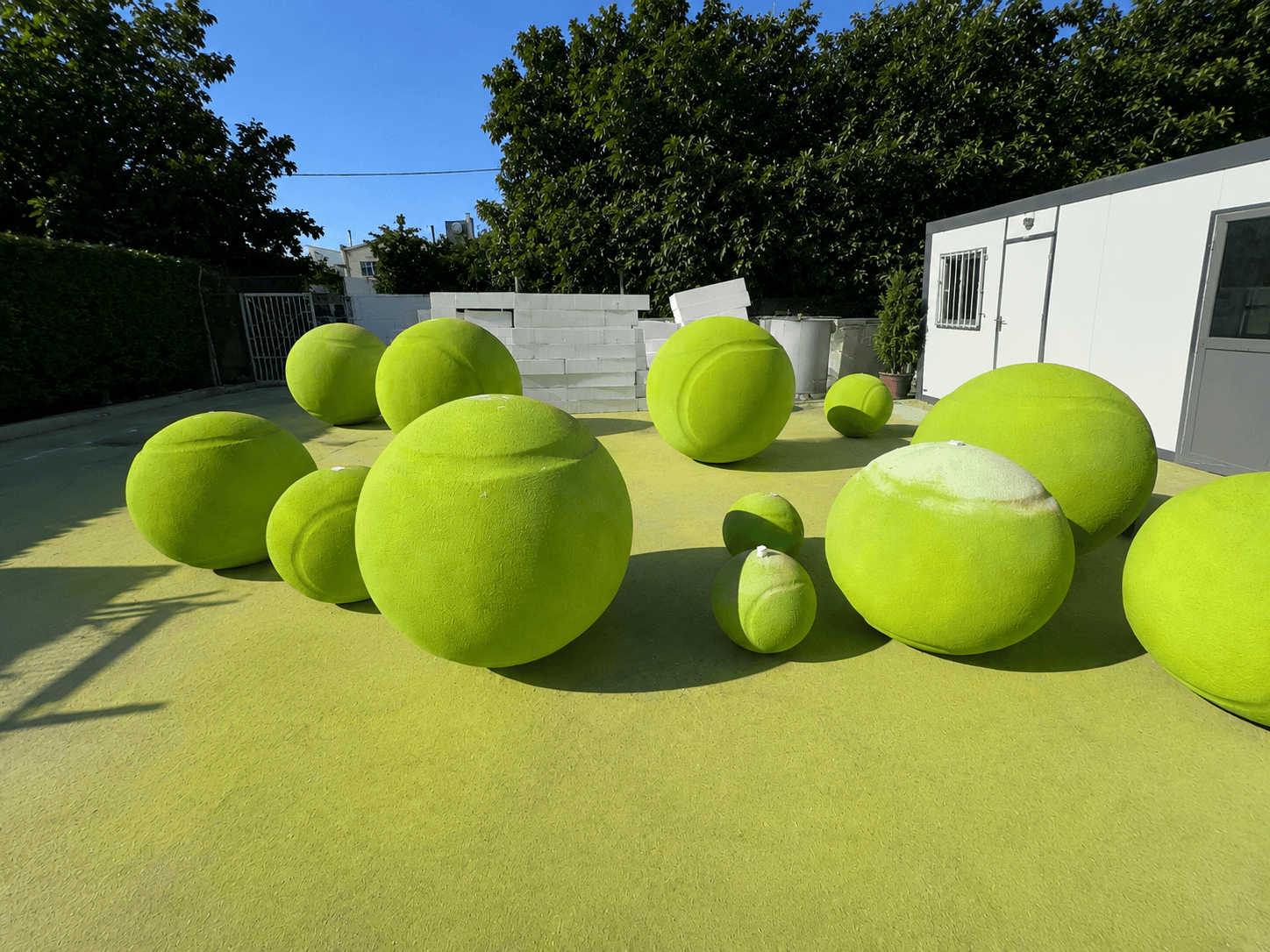 Oversized green tennis ball display objects arranged in an outdoor production area
