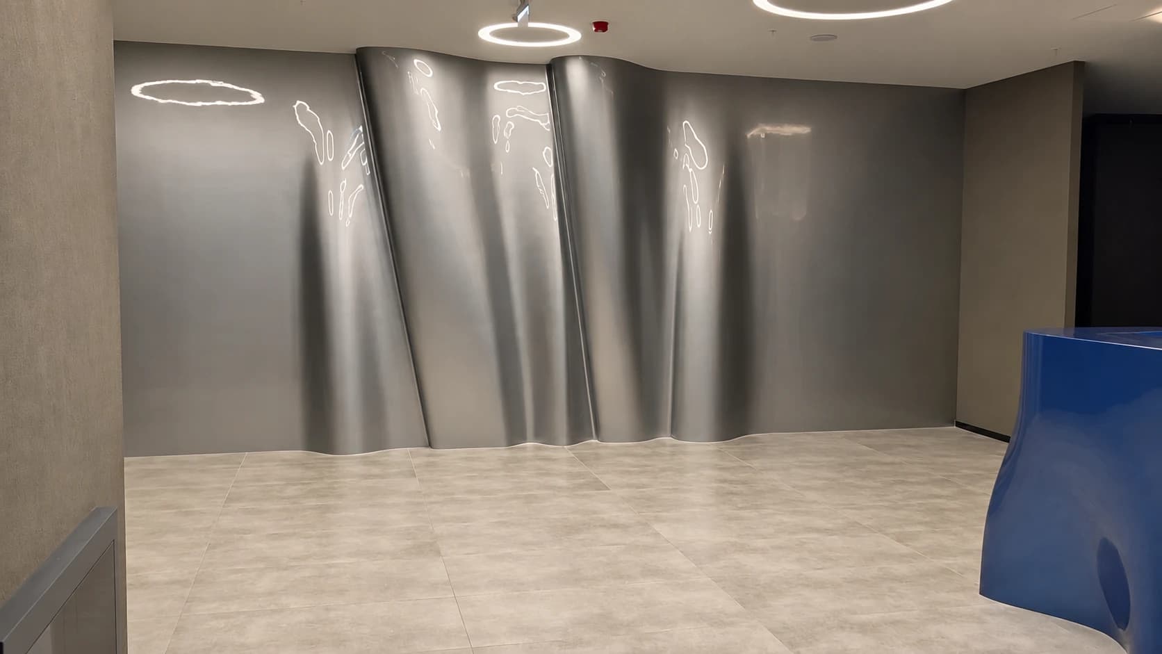 Wide view of silver-grey wall panels with flowing vertical curves